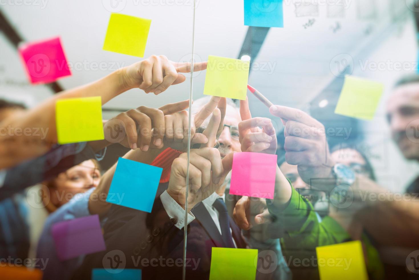 équipe de gens à travail dans le Bureau indique avec leur main un adhésif Remarque sur le verre photo