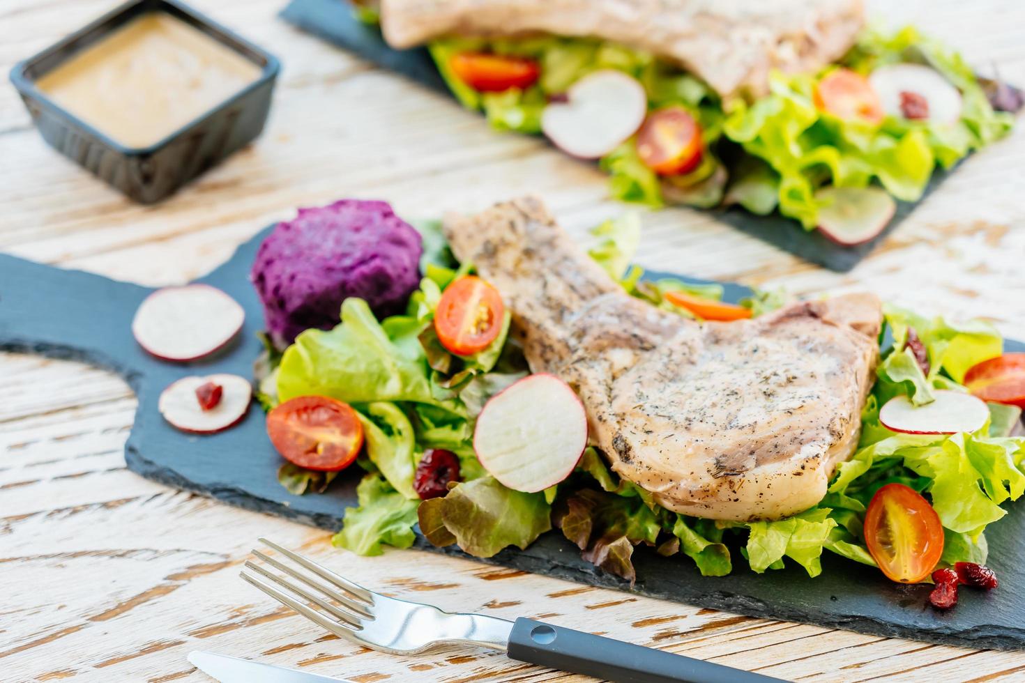 Steak de viande de côtelette de porc barbecue grillé sur plaque noire avec des légumes photo