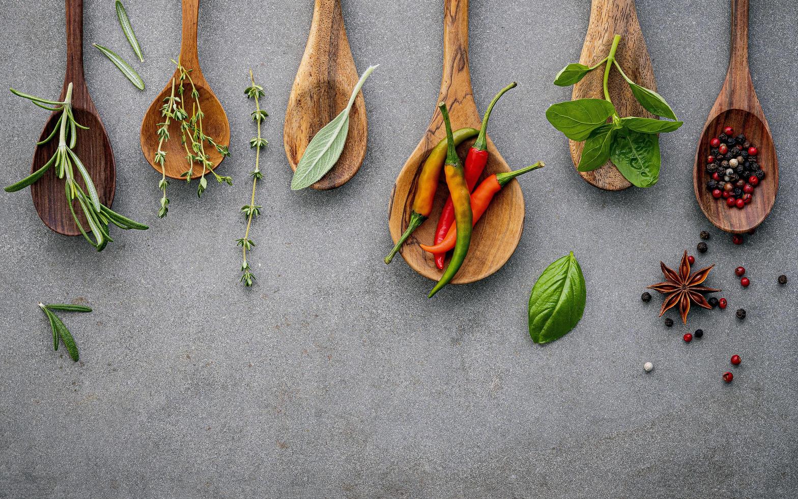 épices et herbes dans des cuillères en bois sur fond gris photo