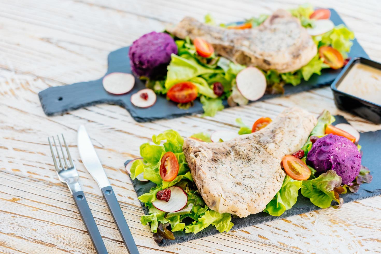 Steak de viande de côtelette de porc barbecue grillé sur plaque noire avec des légumes photo