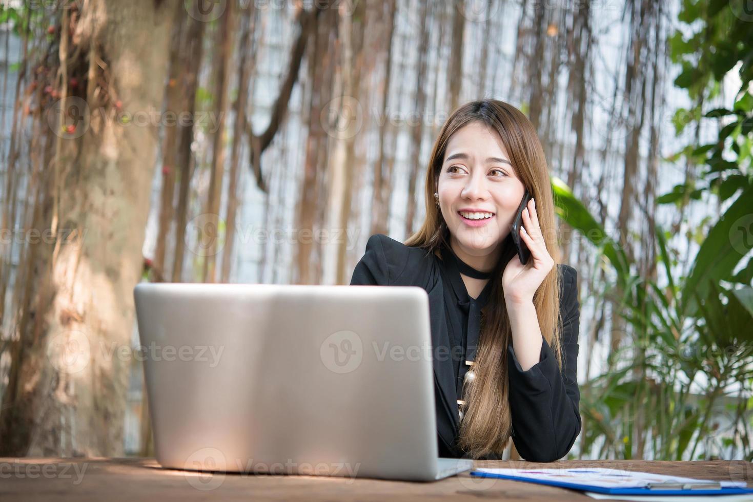 jeune femme d'affaires parlant au téléphone alors qu'elle était assise sur son lieu de travail photo