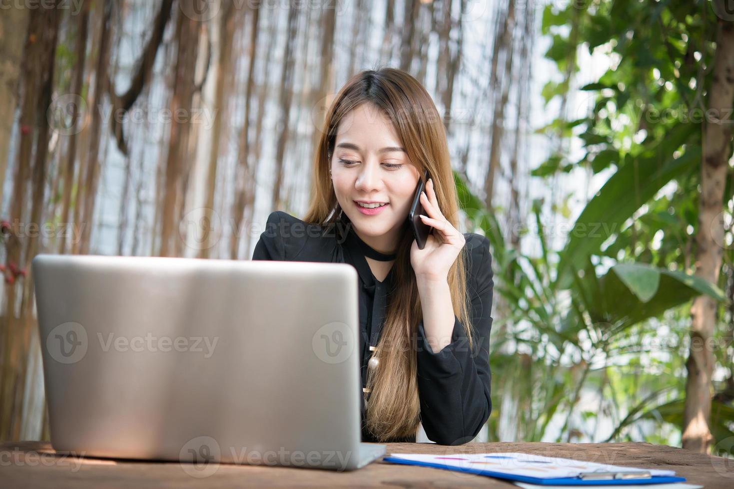 jeune femme d'affaires parlant au téléphone alors qu'elle était assise sur son lieu de travail photo