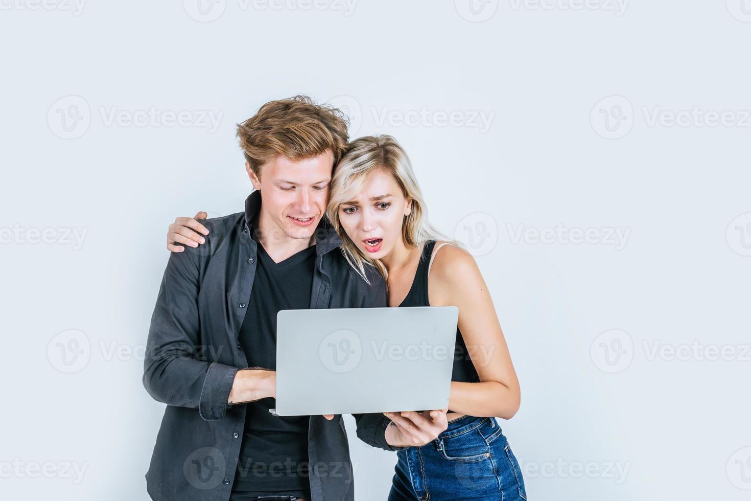 Portrait d'heureux jeune couple à l'aide d'un ordinateur portable en studio photo