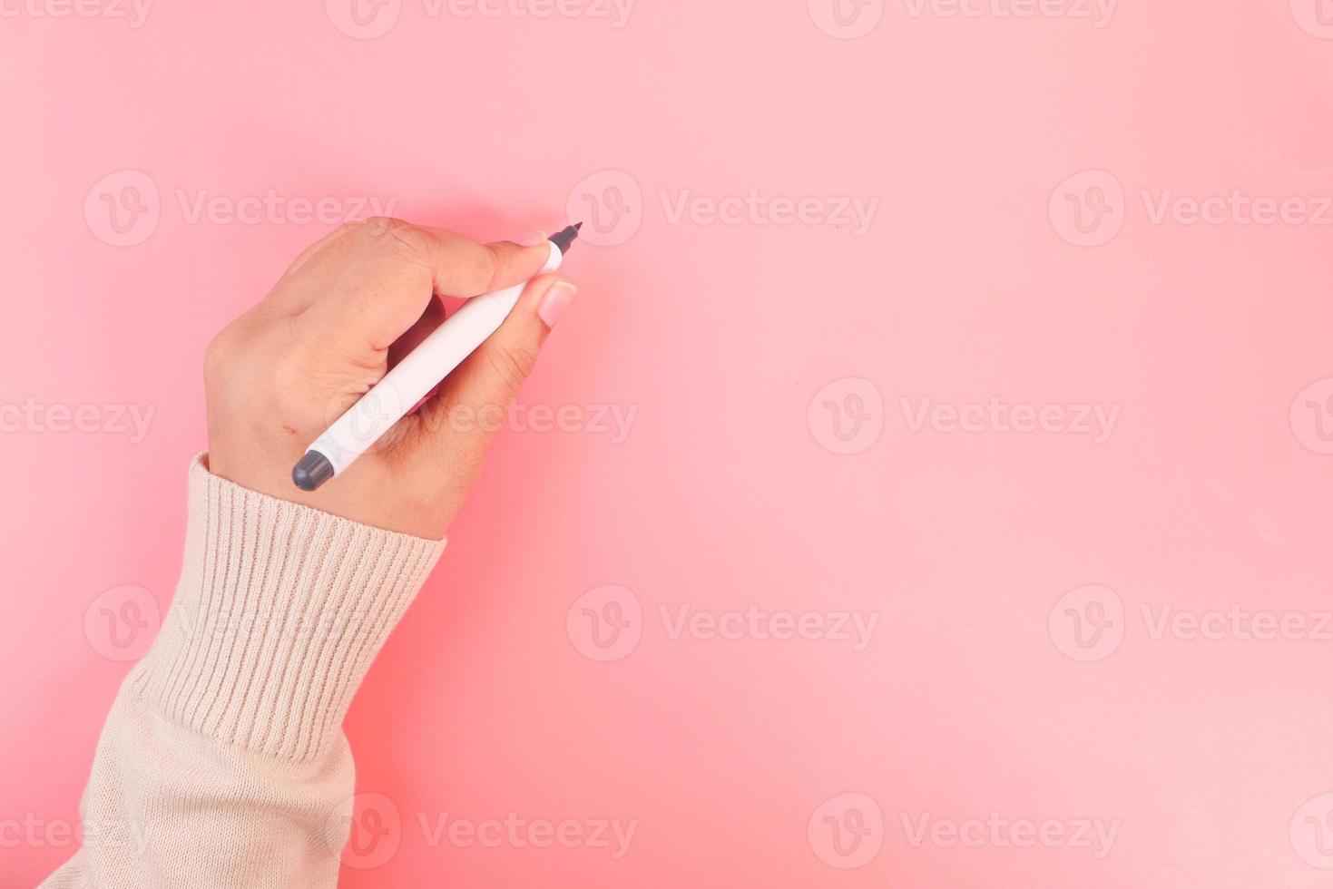 femmes écrivant avec un stylo sur fond rose photo