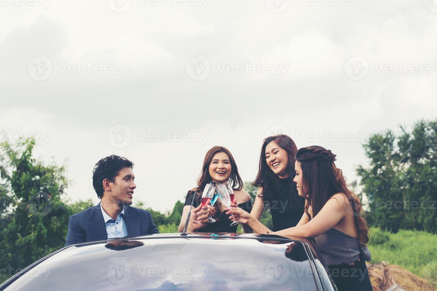 Heureux amis adolescents s'amusant assis sur la voiture le long de la route de campagne photo