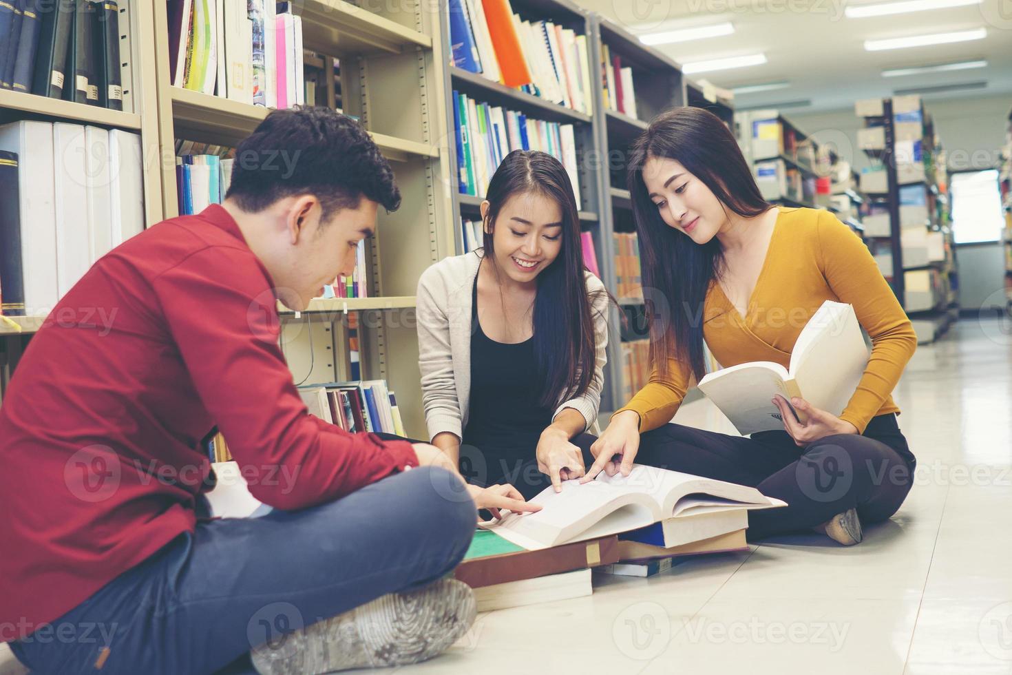 Groupe d'étudiants heureux avec des livres se préparant à l'examen dans la bibliothèque photo