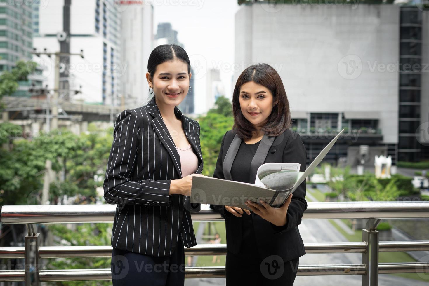 Businesswomen discuter de la paperasse ensemble contre la balustrade photo