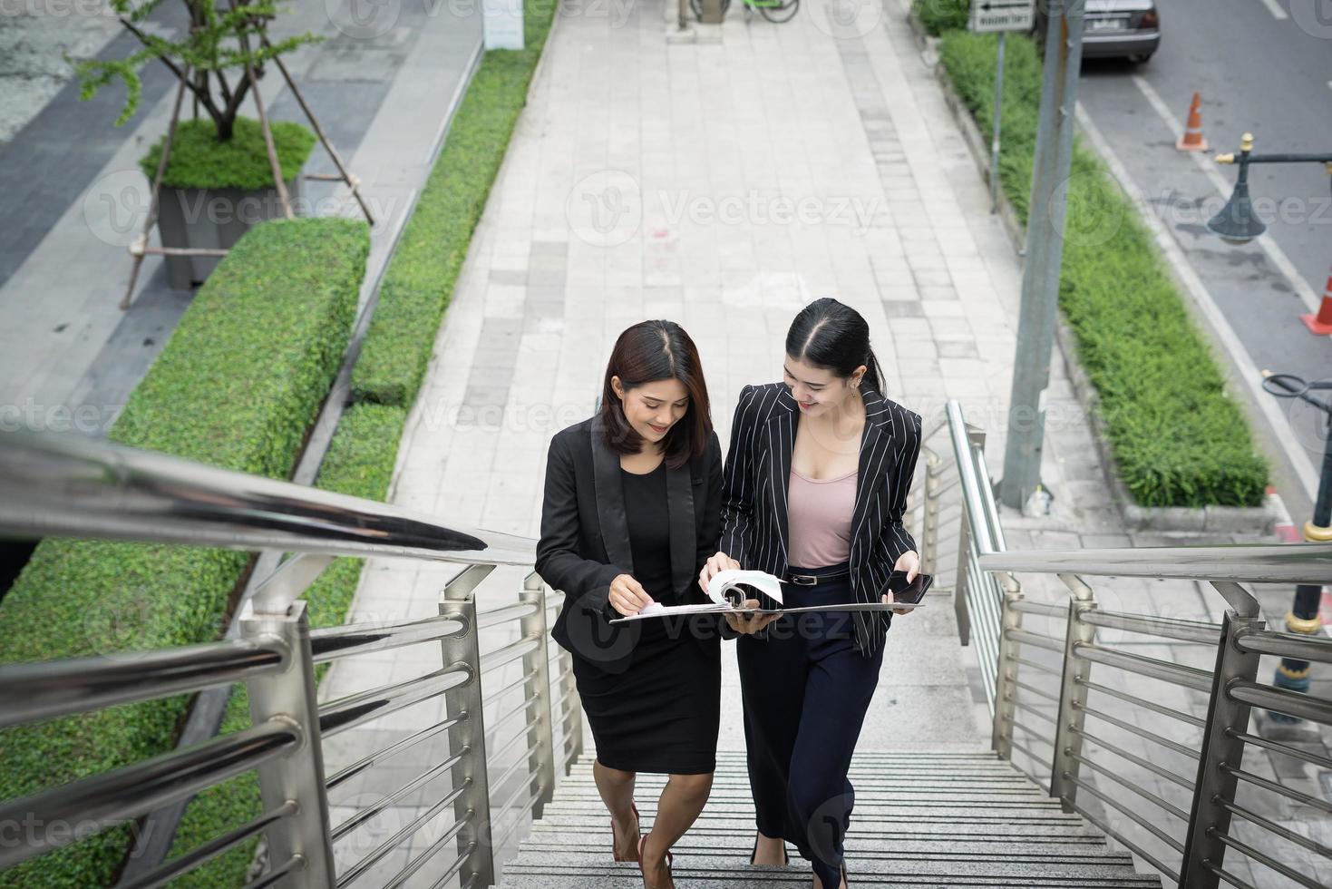Les jeunes femmes d'affaires asiatiques avec des documents marchant dans les escaliers photo