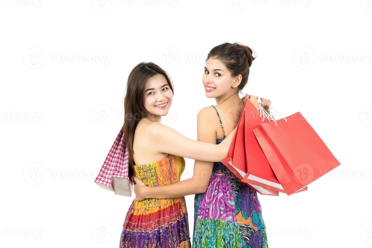 Deux jeunes femmes portant des sacs à provisions isolés sur fond blanc photo