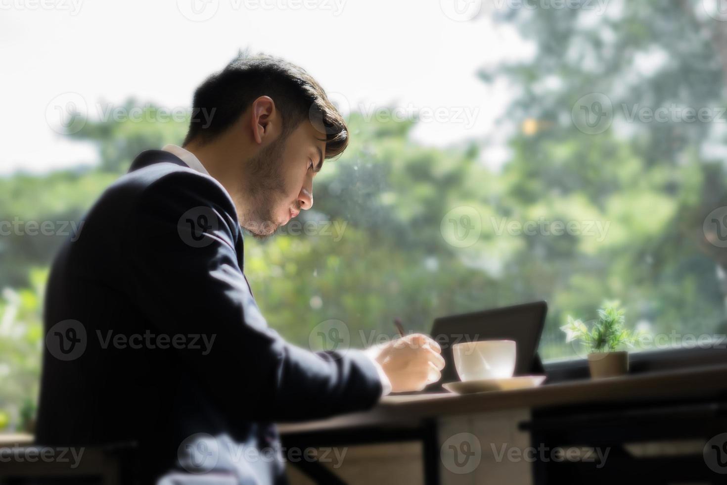 jeune homme d'affaires portant un costume et utilisant un ordinateur portable dans un café photo