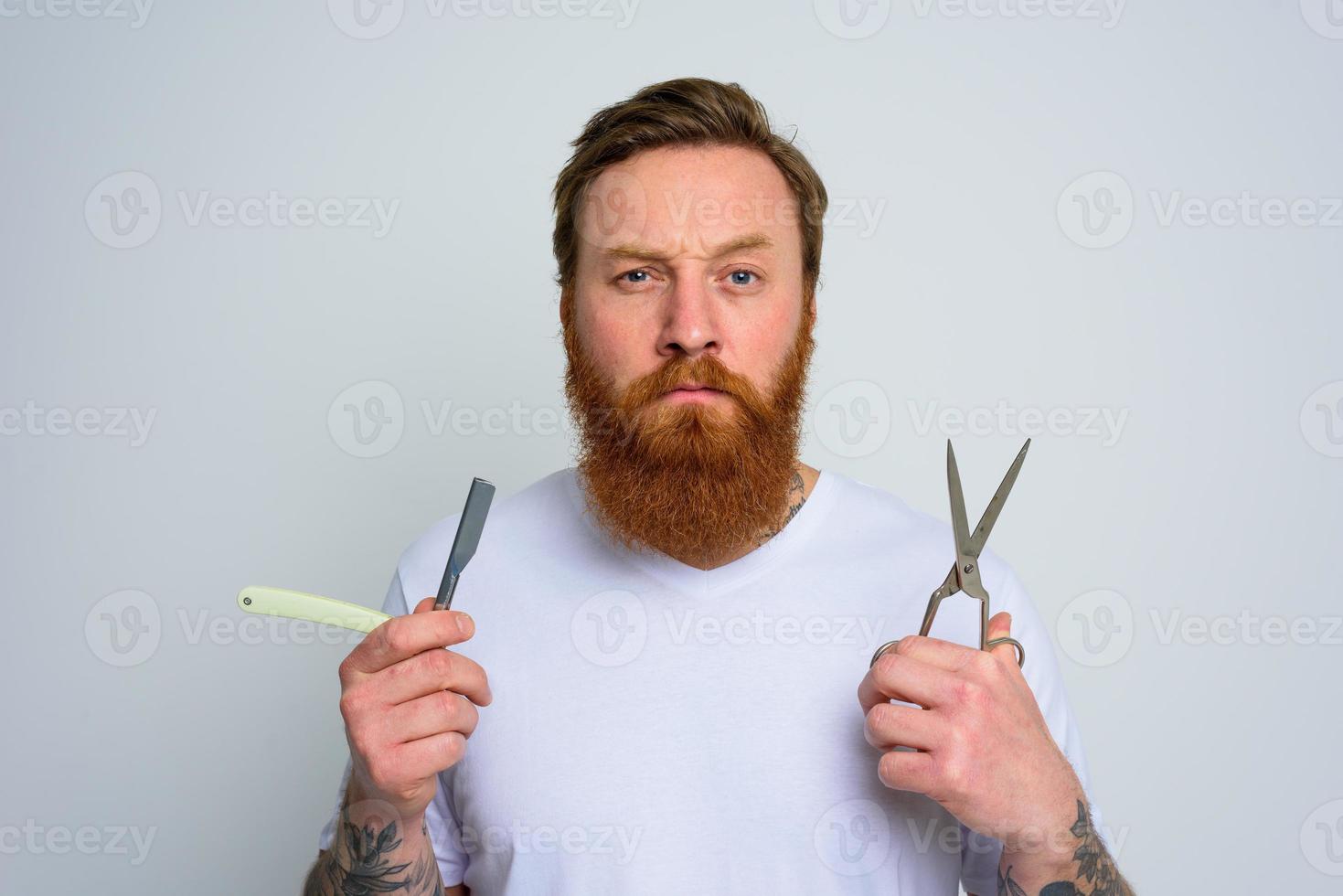 inquiet homme avec les ciseaux et lame est prêt à Couper le barbe photo