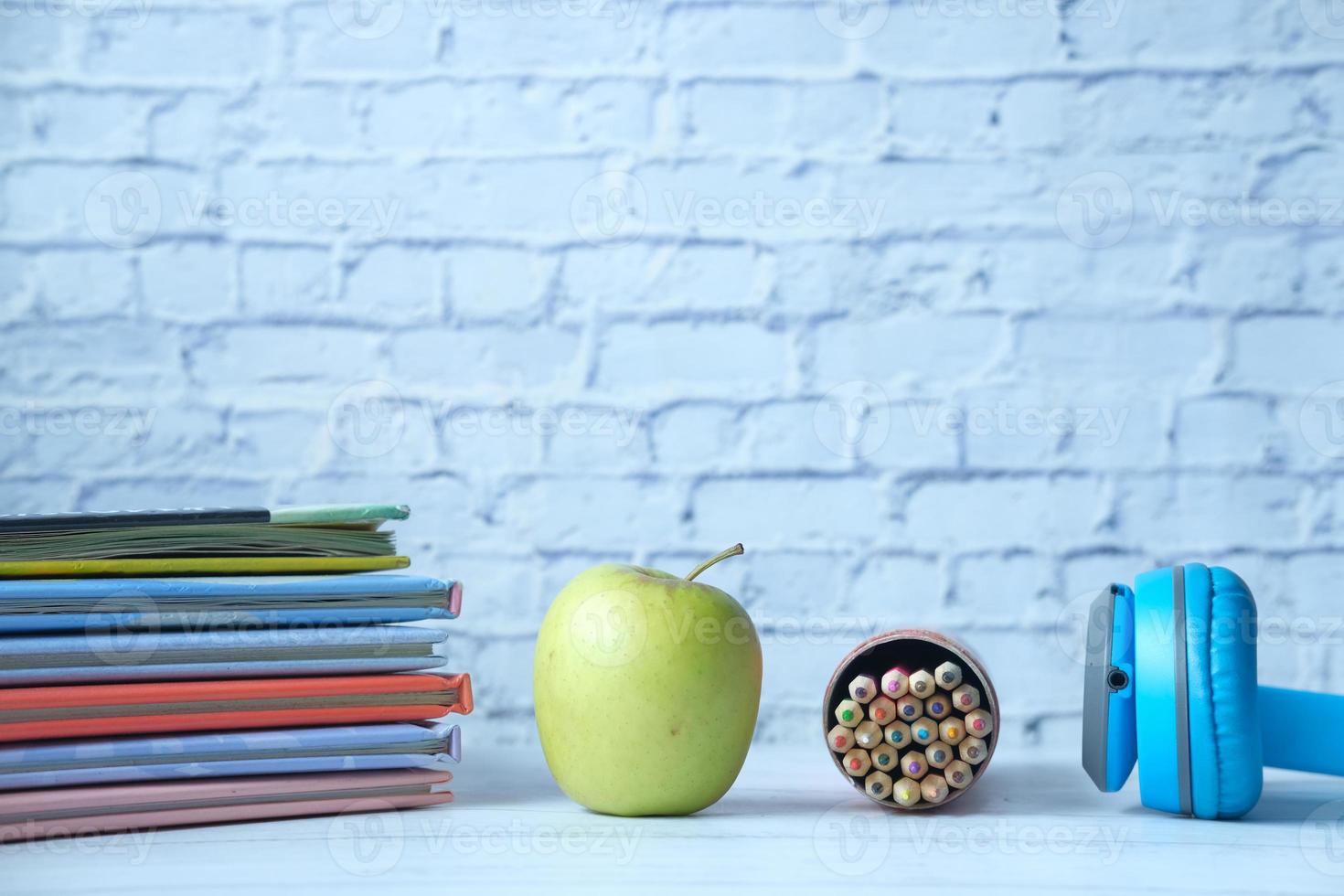 pomme et livres et crayons sur table photo