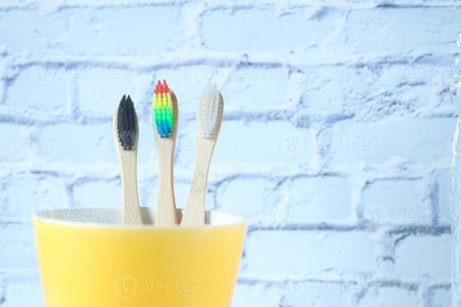 Brosses à dents colorées dans une tasse contre un mur photo