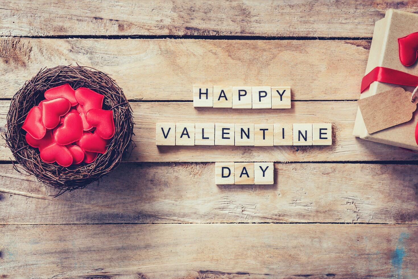 cadeau boîte et rouge cœur dans nid avec en bois texte content Valentin journée sur bois table Contexte. photo