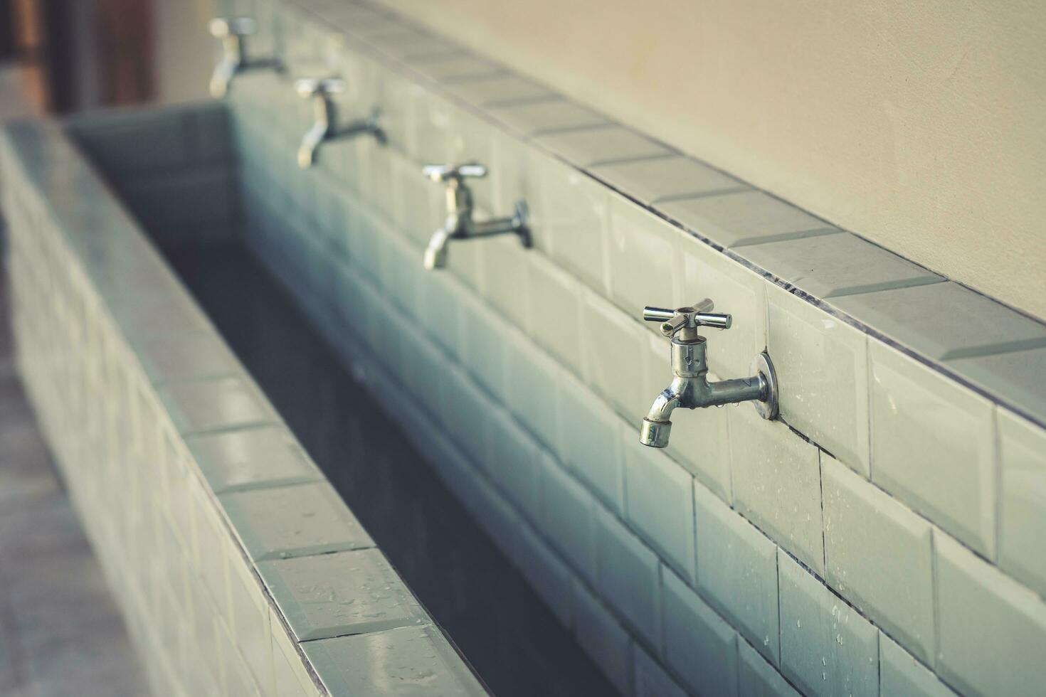 rangée de acier robinets dans une grand salle de bains photo