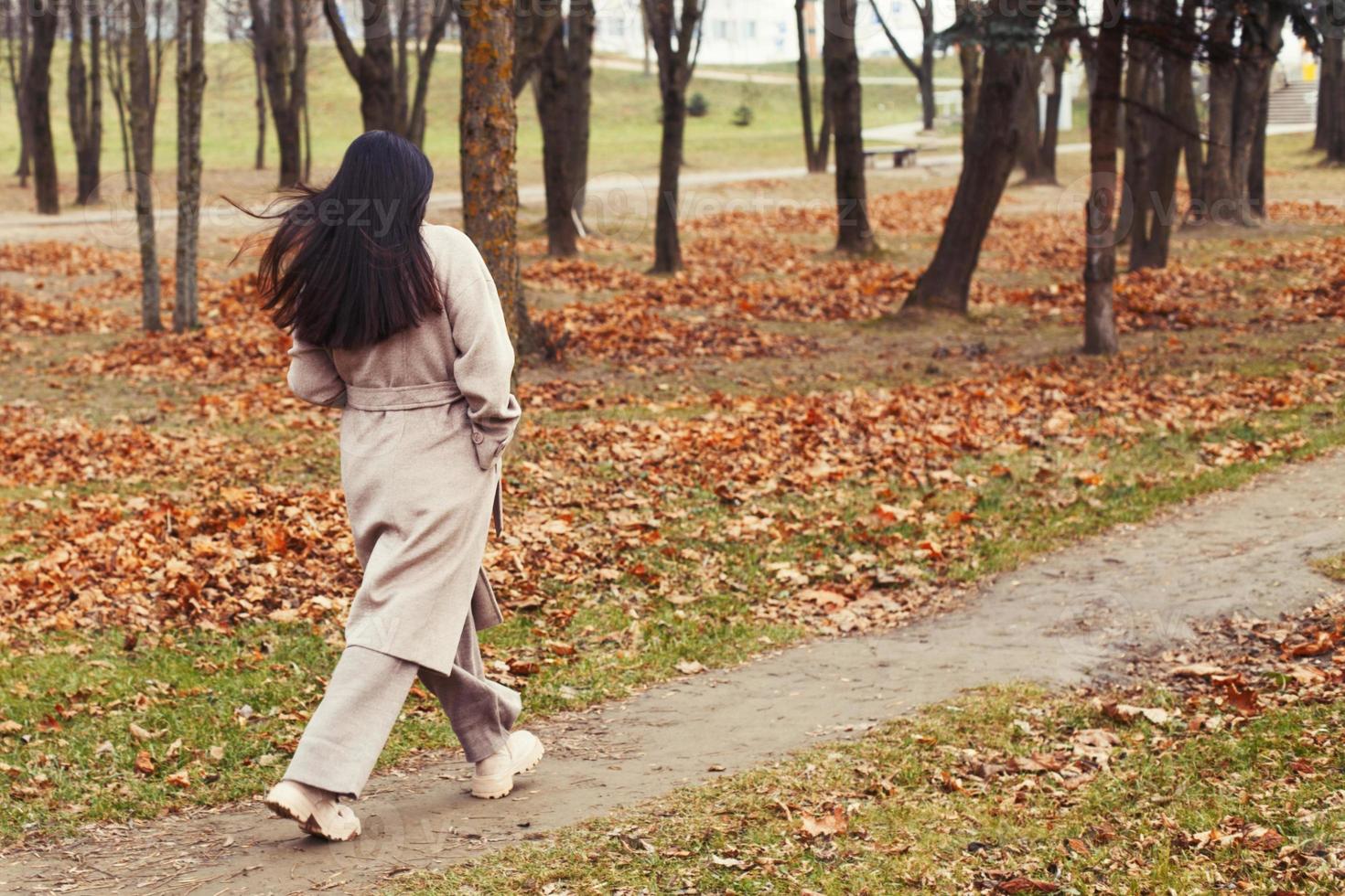 femme dans une gris manteau en marchant dans le l'automne parc photo