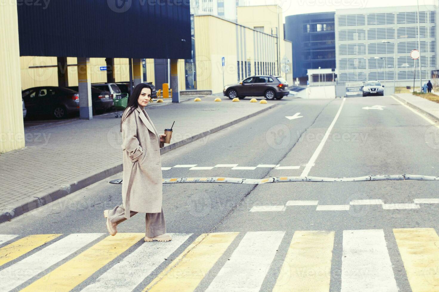 femme en portant café et traversée le route à piéton traversée contre Urbain ville Contexte photo