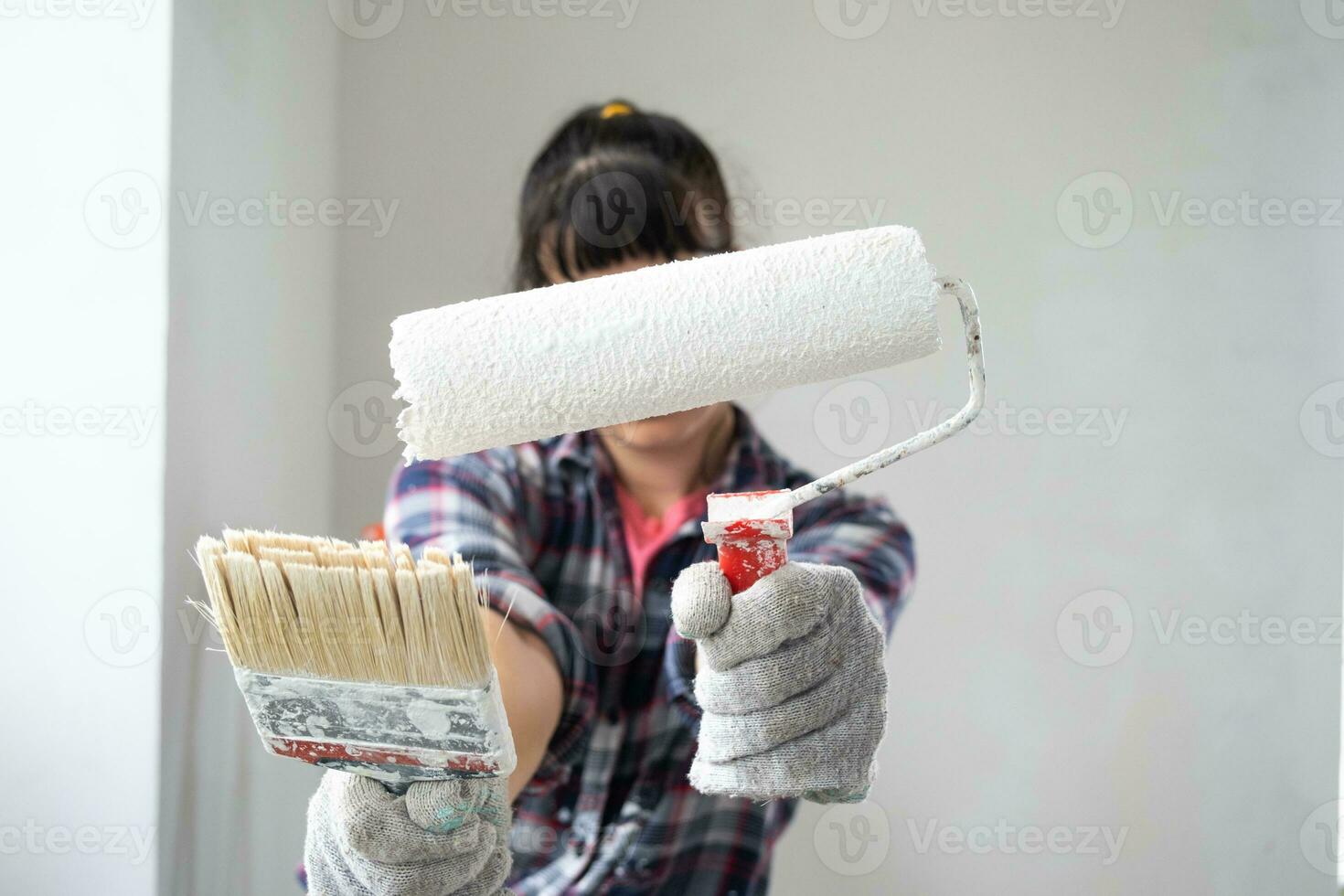 perplexe femme dans peindre rouleau et blanc peindre pour des murs dans mains fermer portrait. construction travail et cosmétique réparations dans loger, mur peinture, teinter, finition travail avec votre posséder mains photo