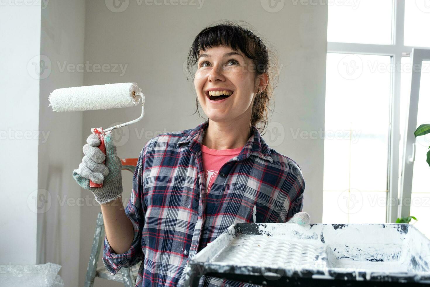 content femme dans peindre rouleau et blanc peindre pour des murs dans mains fermer portrait. construction travail et cosmétique réparations dans loger, mur peinture, teinter, finition travail avec votre posséder mains photo