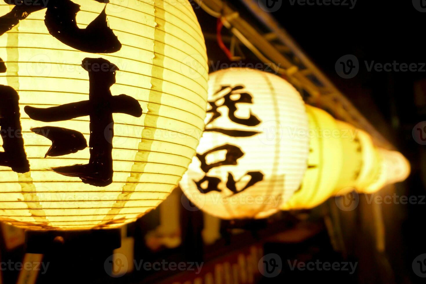 fermer noir Japonais des textes sur papier lanterne pendaison en dessous de Japonais restaurant avant-toits sur nuit temps. photo