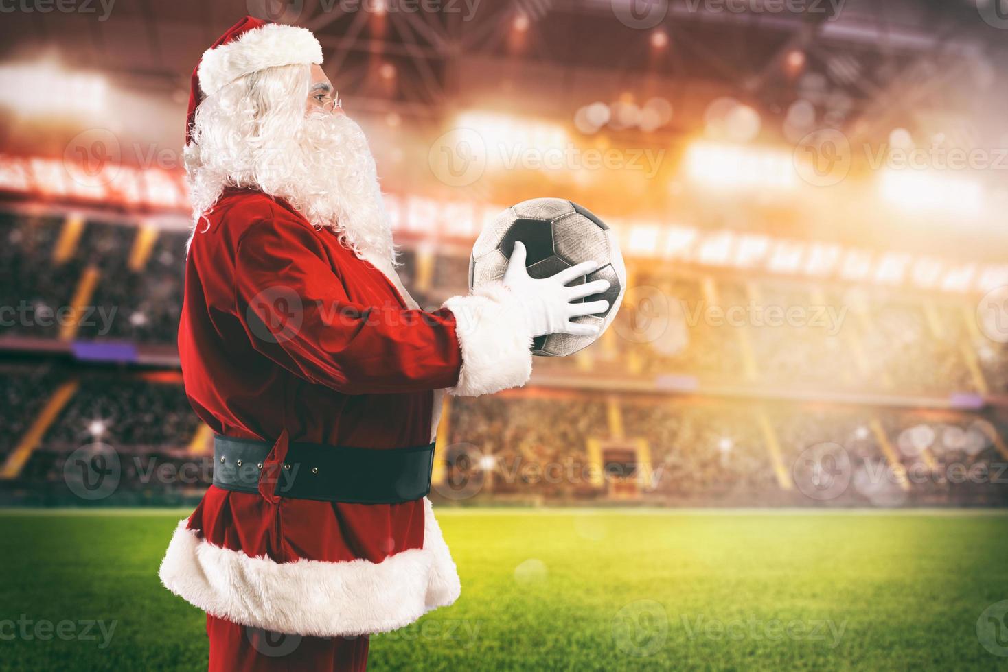 Père Noël claus avec une football Balle dans le sien mains à l'intérieur une football stade photo