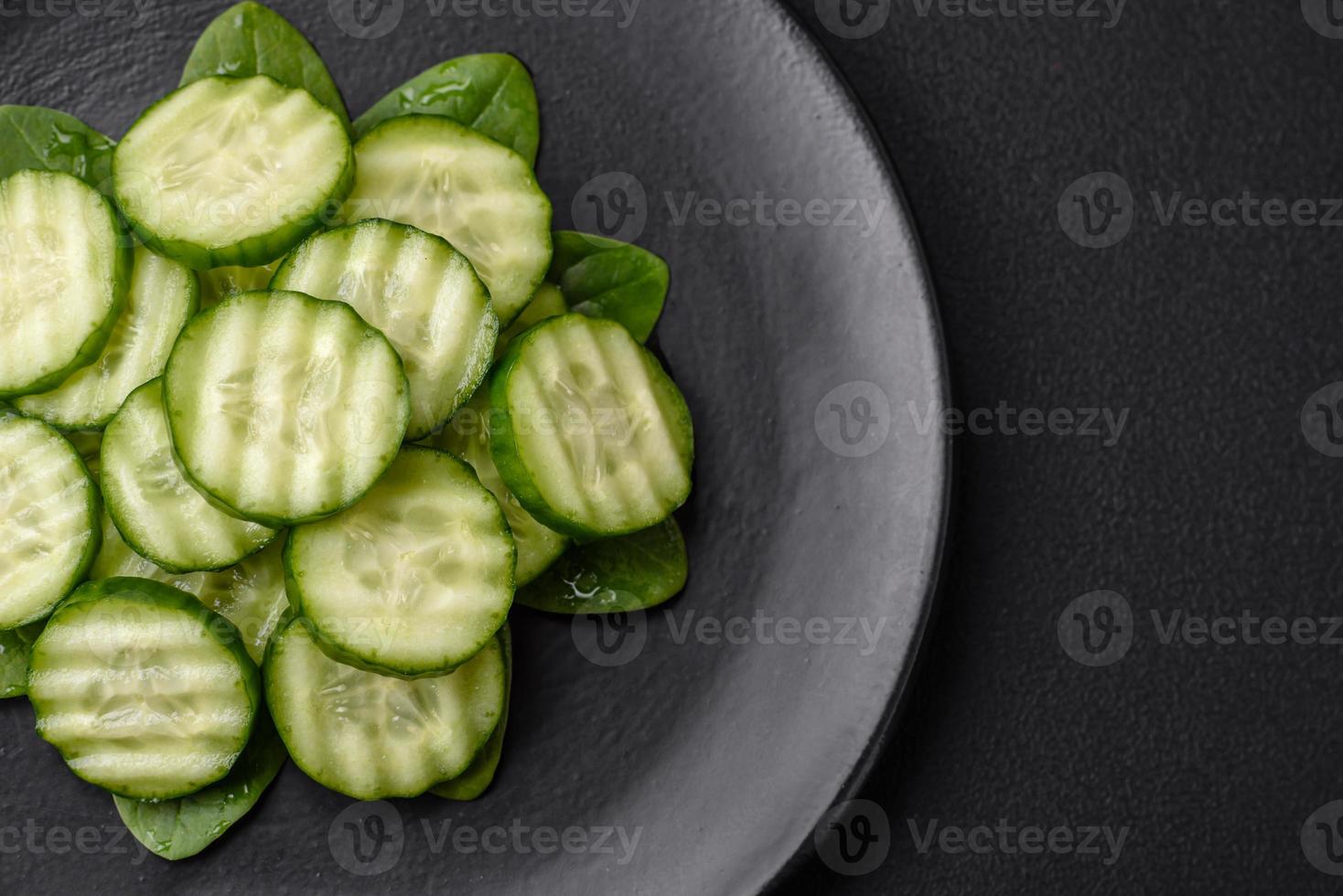 délicieux en bonne santé brut concombre tranché sur une noir céramique assiette photo