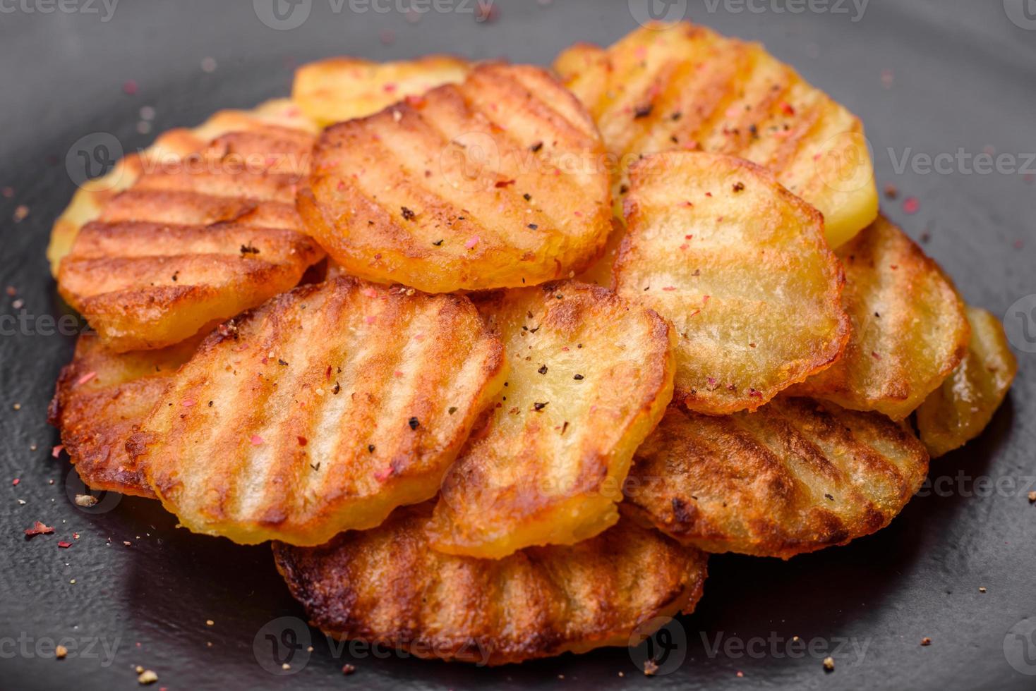 délicieux croustillant frit patates dans tranches sur une noir céramique assiette photo