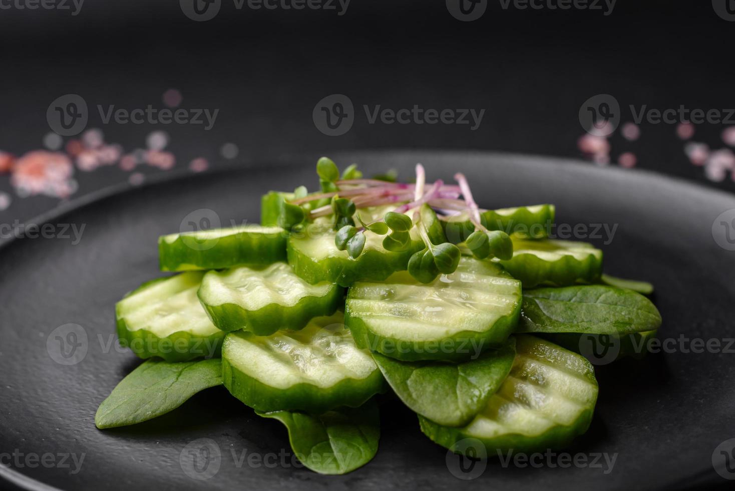 délicieux en bonne santé brut concombre tranché sur une noir céramique assiette photo