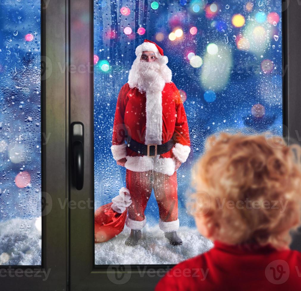 enfant observe Père Noël claus par le les fenêtres photo