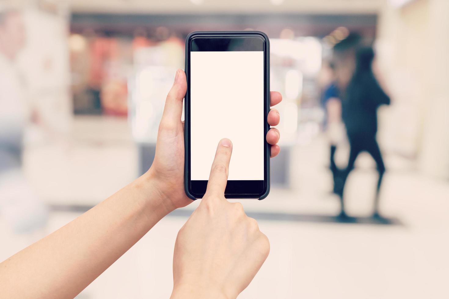 main femme en portant et en utilisant téléphone avec flou Contexte dans achats centre commercial. photo