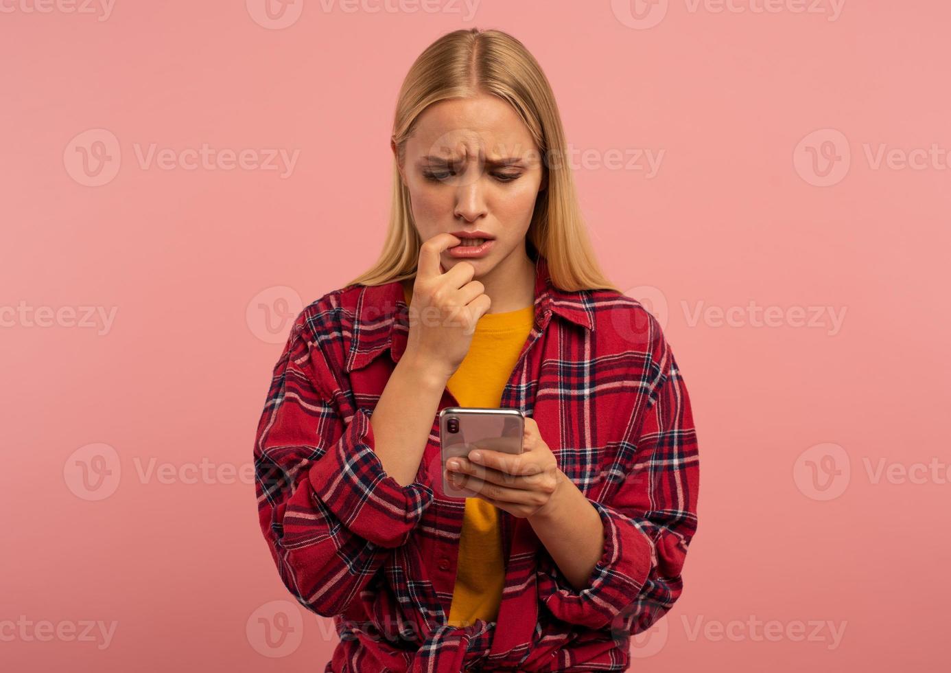 fille avec sa téléphone intelligent. effrayé et peur expression. rose Contexte photo