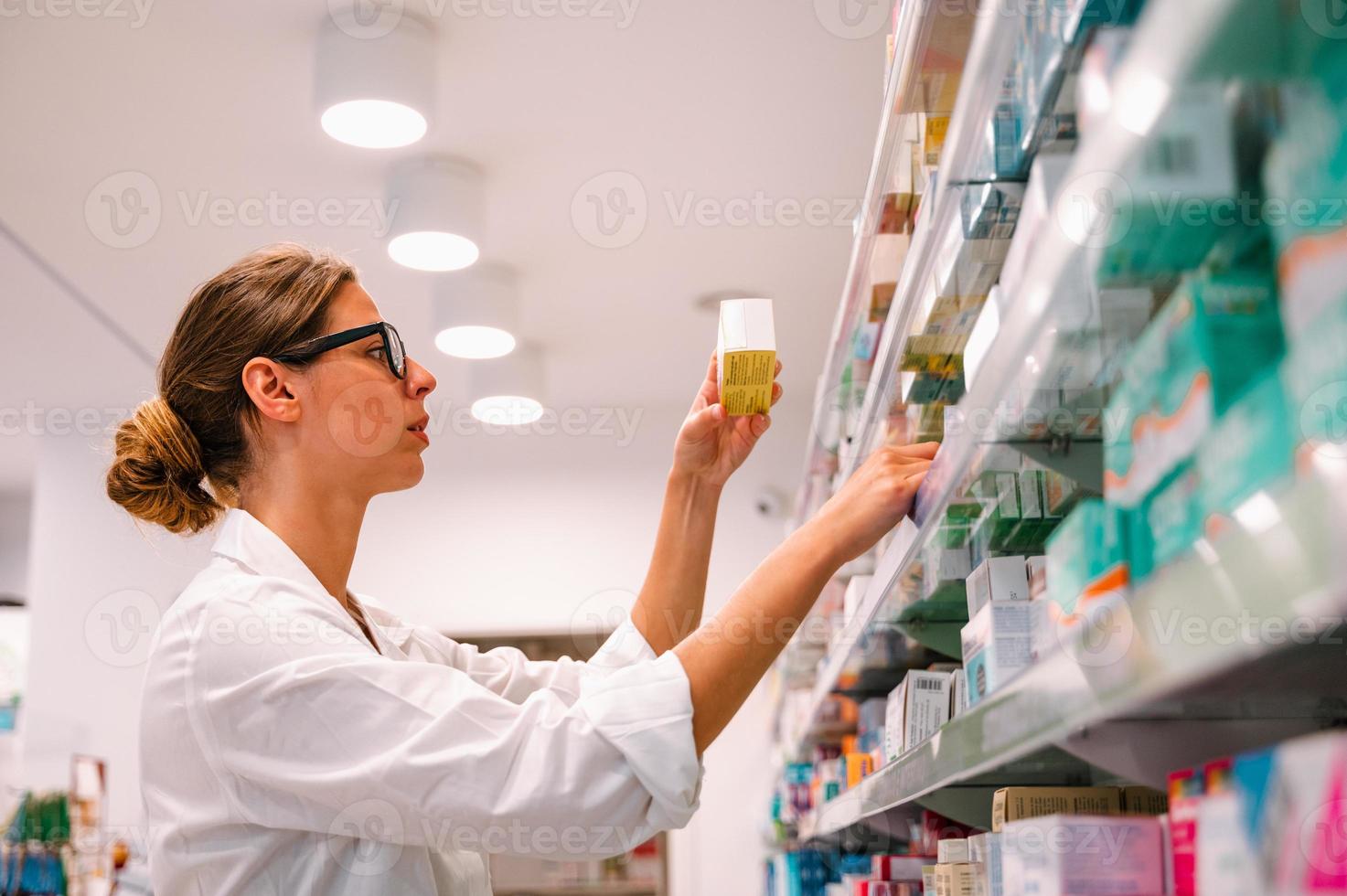 femme travail dans le pharmacie regards pour le médicament photo