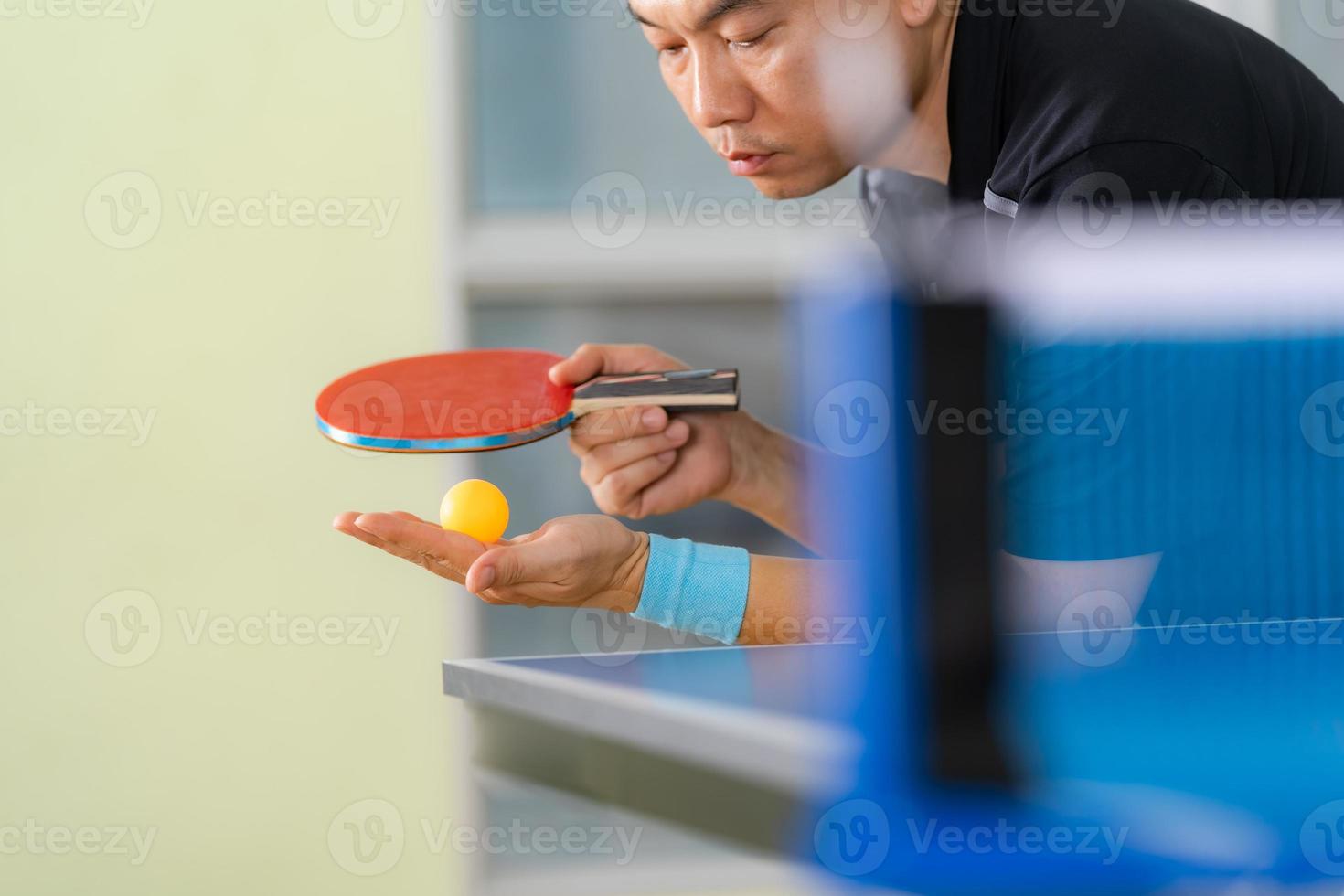 Homme jouant au tennis de table avec raquette et balle dans une salle de sport photo