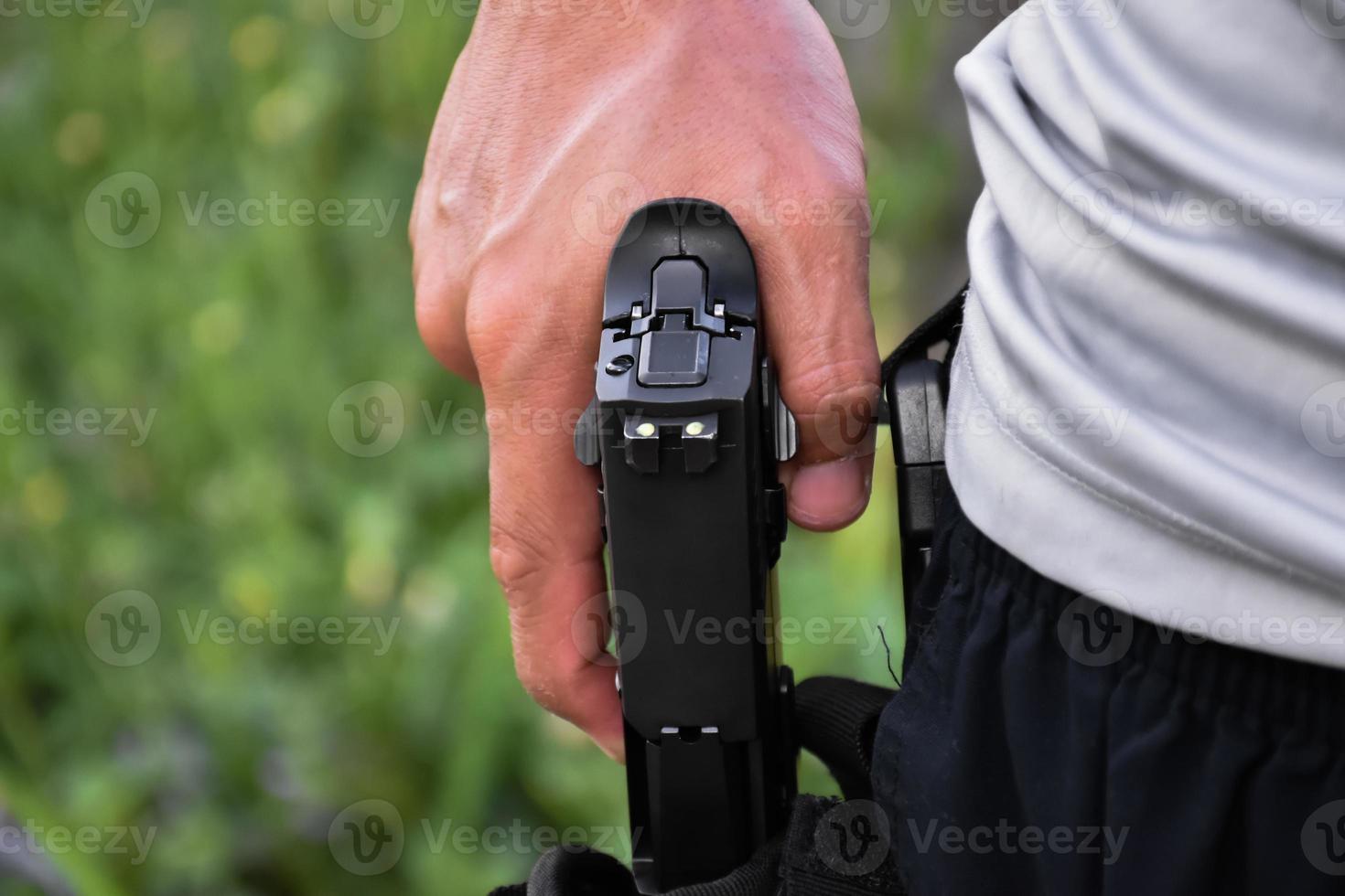Pistolet automatique de 9 mm tenant dans la main droite du tireur, concept de sécurité, vol, gangster, garde du corps dans le monde entier. mise au point sélective sur le pistolet. photo