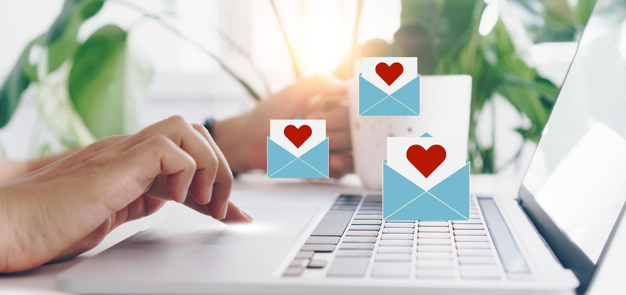 clavier de saisie à la main avec ordinateur portable avec lettre d'amour des médias sociaux envoyer des icônes Saint Valentin. photo