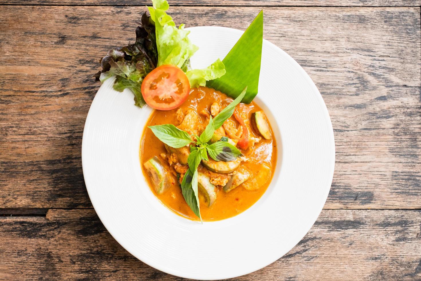 Vue de dessus du curry rouge avec du poulet sur un fond en bois photo