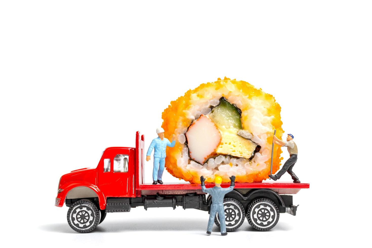 Personnes miniatures avec des rouleaux de sushi sur un camion isolé sur fond blanc, concept de livraison de nourriture photo