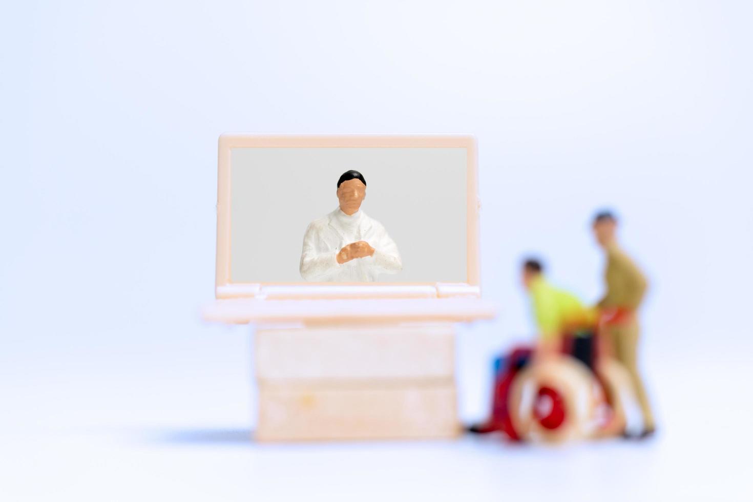 Personnes miniatures d'un patient de sexe masculin en consultation avec un médecin à l'aide d'un appel vidéo sur un ordinateur portable, concept de médecin en ligne photo