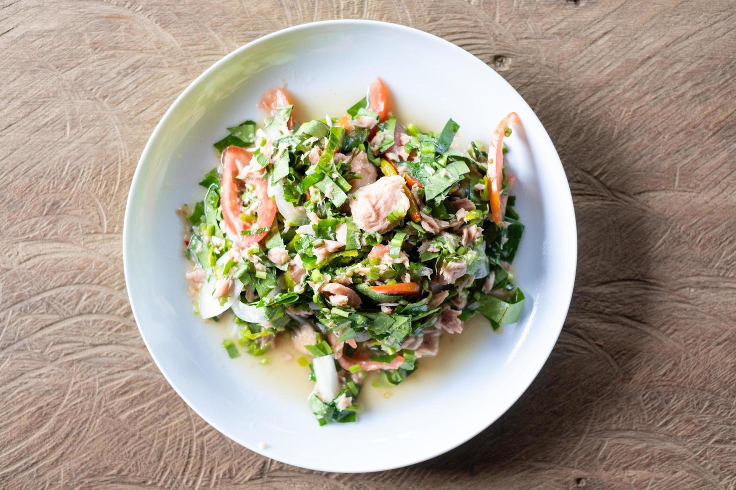 Vue de dessus des feuilles de thé vert avec salade de thon sur une table en bois photo