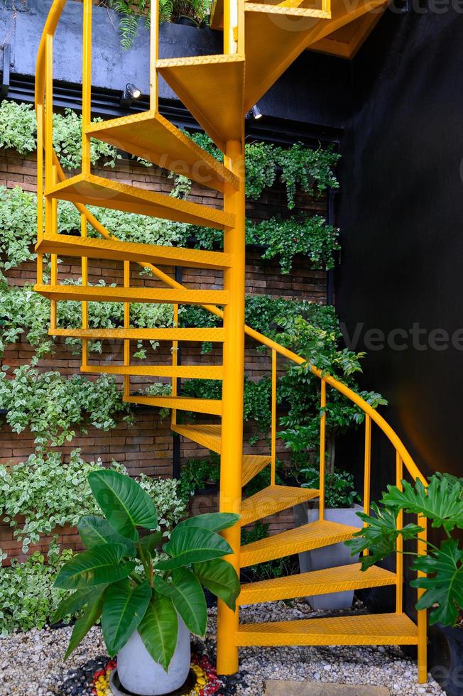 Escalier en colimaçon jaune avec des plantes sur le mur de briques photo