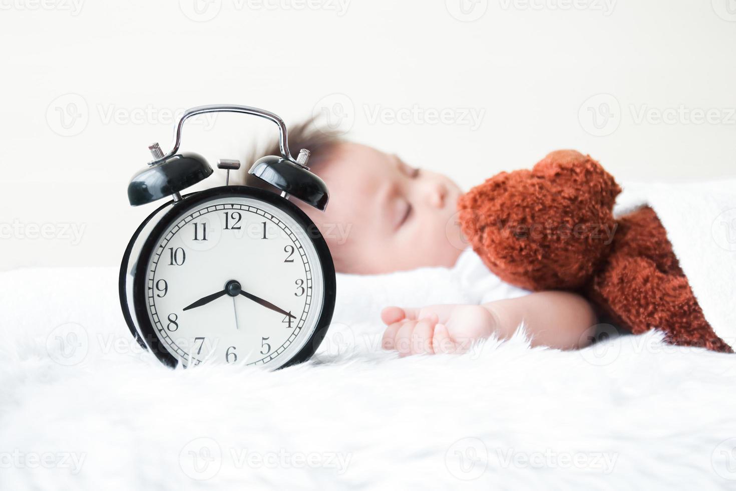 le peu garçon dormi dans lit avec une nounours ours en train de dormir comme une ami. il est malade avec une froid. le Matin l'horloge à 8h20 un m garde d'enfants concept photo