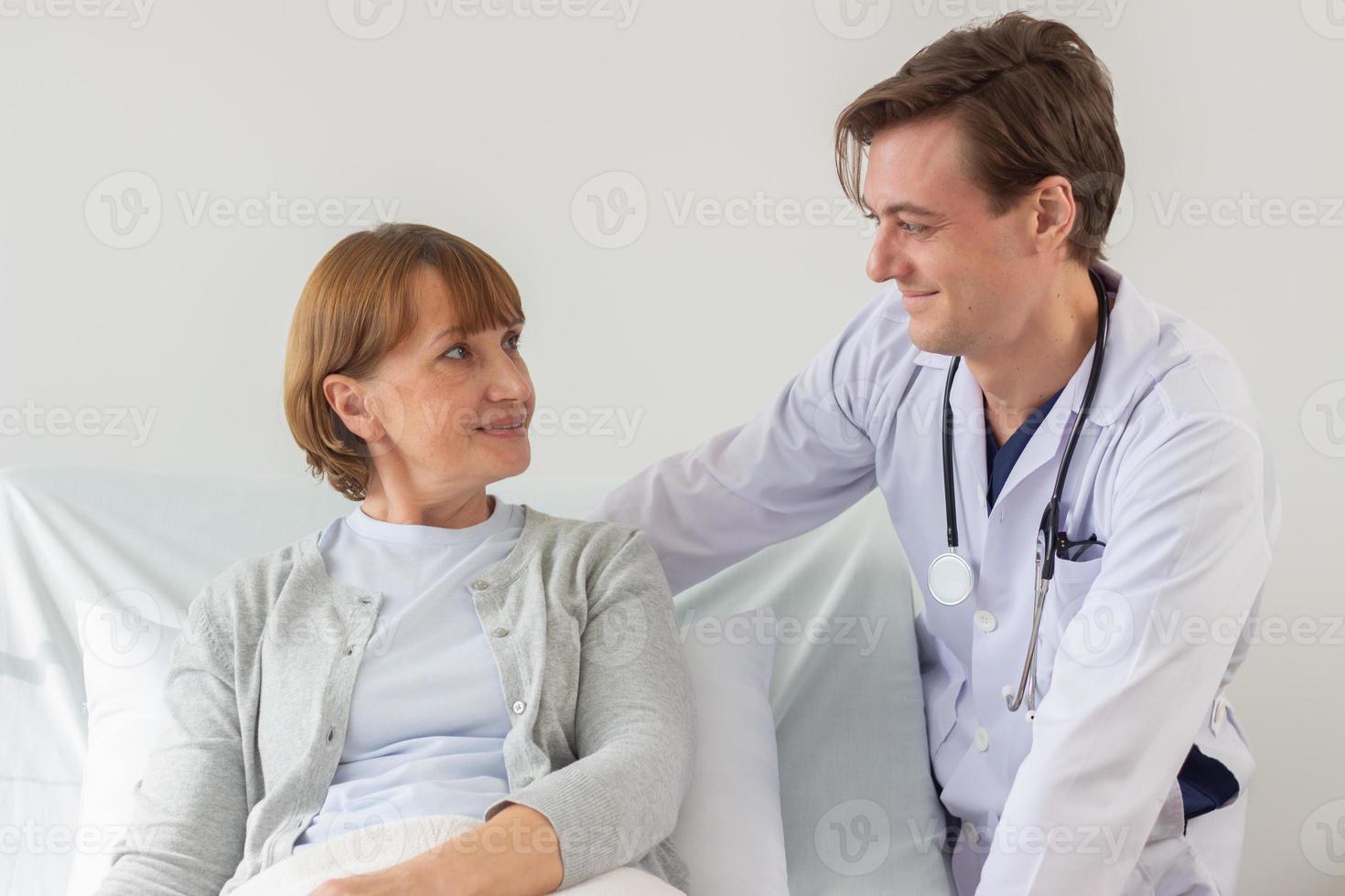 le médecin est examiner le patient dans le hôpital. caucasien médecin portant robe et écoute dispositif et une femelle patient à la recherche à chaque autre à le hôpital. photo