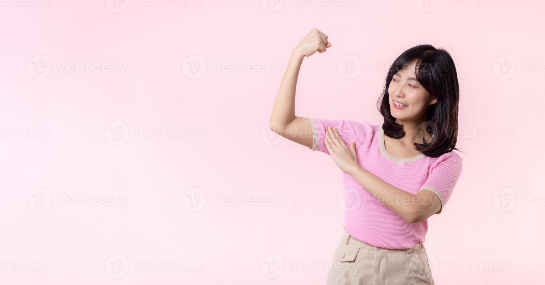 portrait Jeune asiatique femme fier et sur de soi montrant fort muscle force bras fléchi poser, se sent à propos sa Succès réalisation. femmes autonomisation, égalité, en bonne santé force et courage concept photo