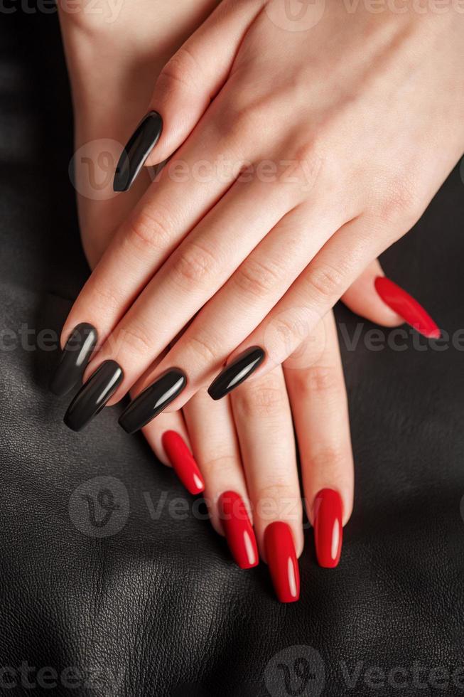 mains d'une jeune fille avec une manucure noire et rouge sur les ongles photo