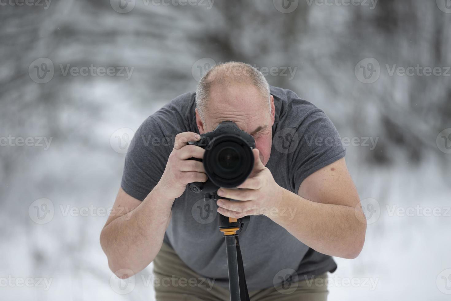 photographe avec une caméra dans le hiver forêt. personnes âgées Masculin photographe. photo