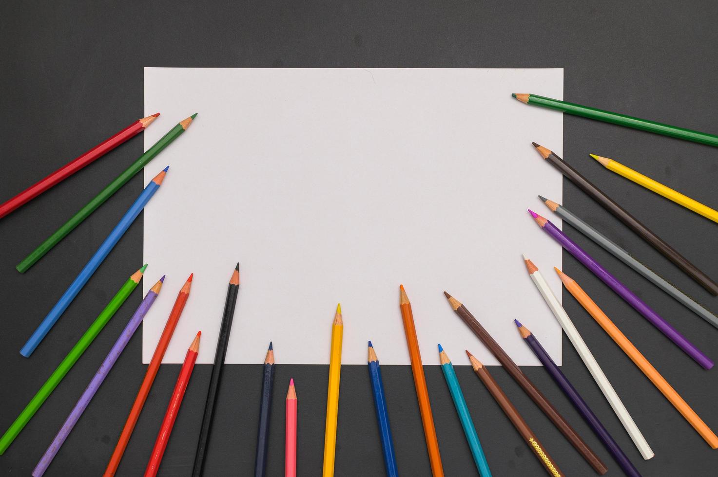 Crayons multicolores et papier blanc sur fond noir photo