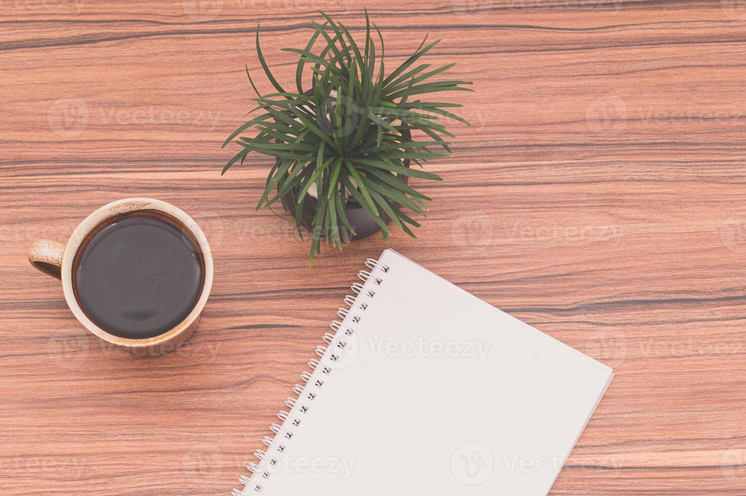 cahier sur le bureau avec du café et une plante photo