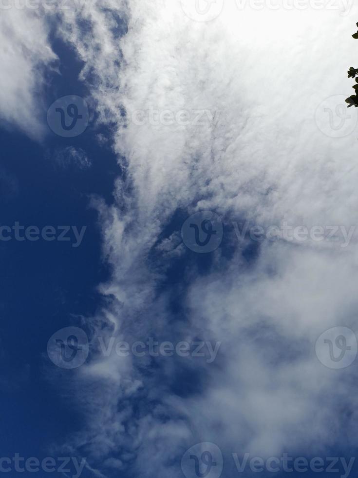 beaux nuages blancs sur fond de ciel bleu profond. de grands nuages doux et moelleux couvrent tout le ciel bleu. photo