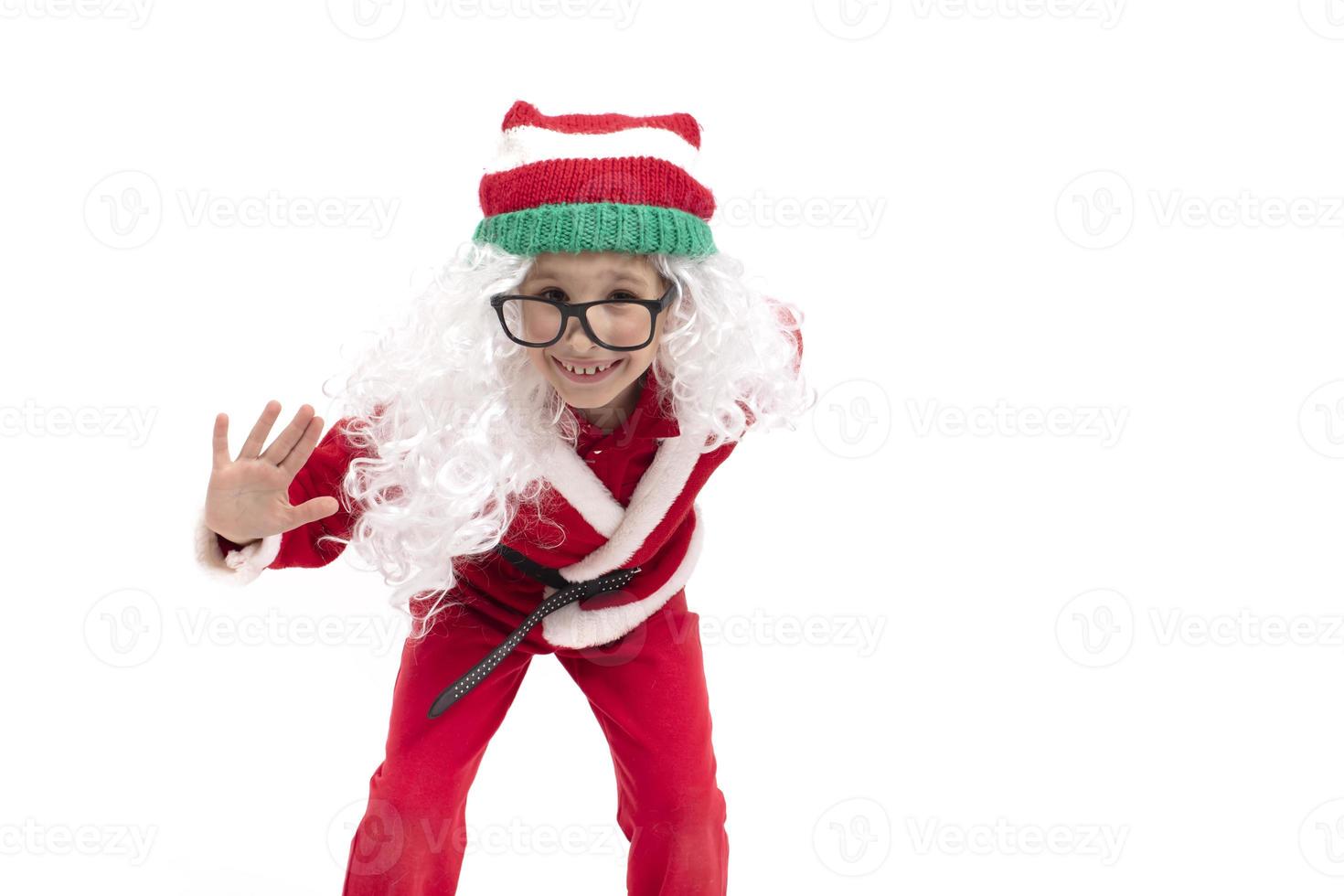 marrant enfant habillé comme Père Noël claus grimaces, pose. Noël garçon dans une chapeau et lunettes. photo