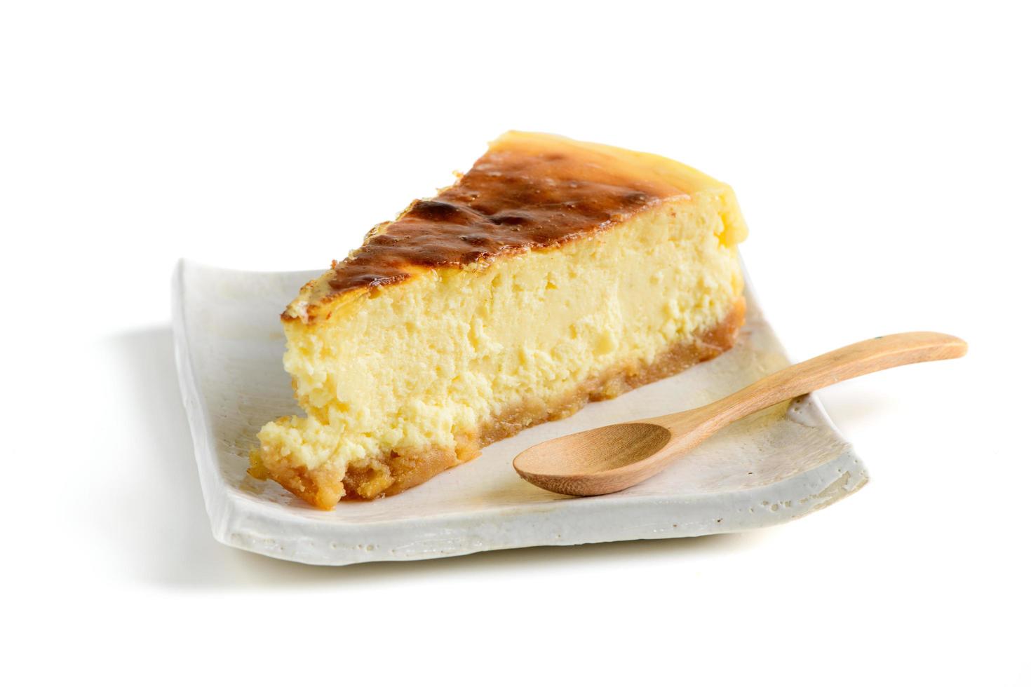 cheesecake tranche, tranche de savoureux gâteau sur blanc assiette et bois cuillère isolé photo